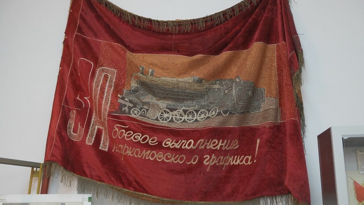 «Железнодорожники Донбасса всегда показывали высокие производственные результаты, за что поощрялись грамотами, вымпелами и переходящим красным знаменем. Автор фото: В. Рудь – (экспонат железнодорожного музея)»